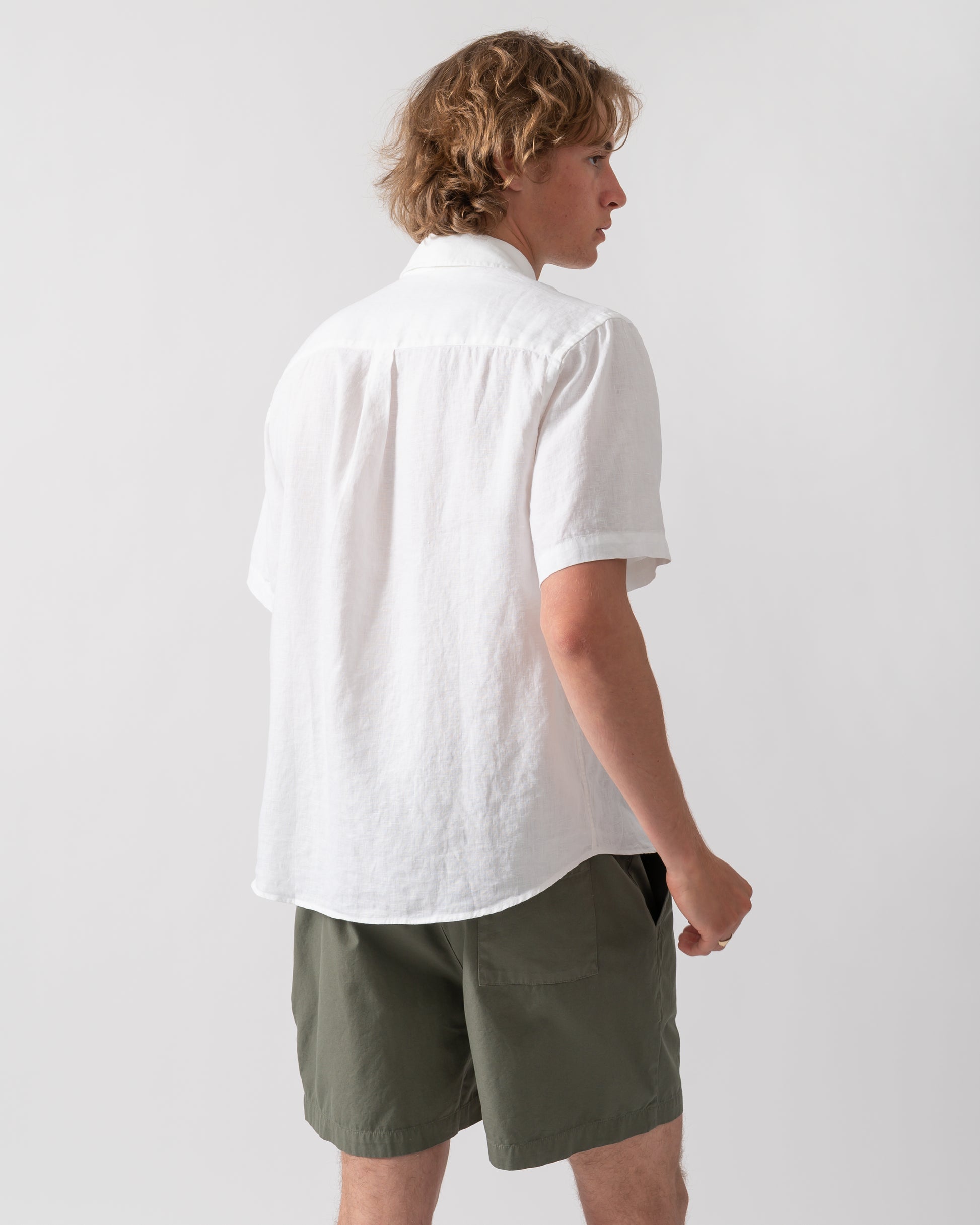 back shot of a model wearing a Colorful Standard Mens Short Sleeve Linen Shirt in Optical White