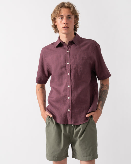 model wearing a Colorful Standard Mens Short Sleeve Linen Shirt in Oxblood Red