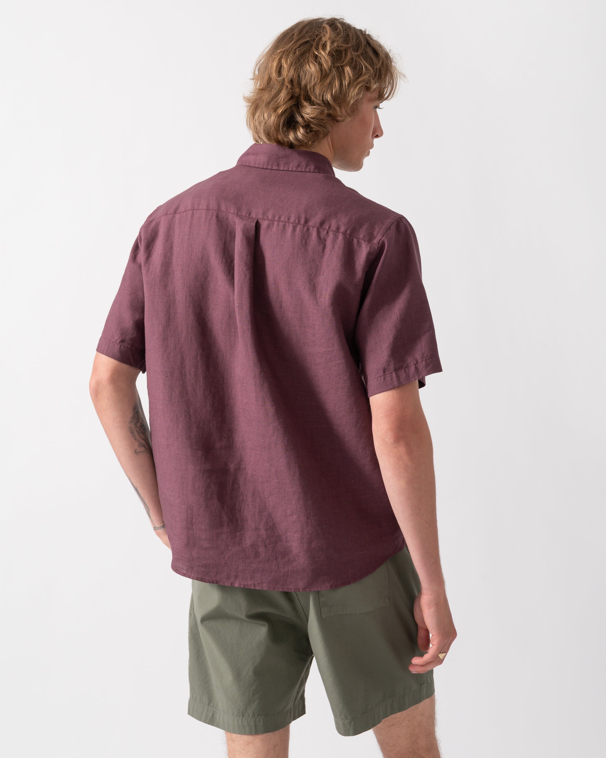 back shot of a model wearing a Colorful Standard Mens Short Sleeve Linen Shirt in Oxblood Red