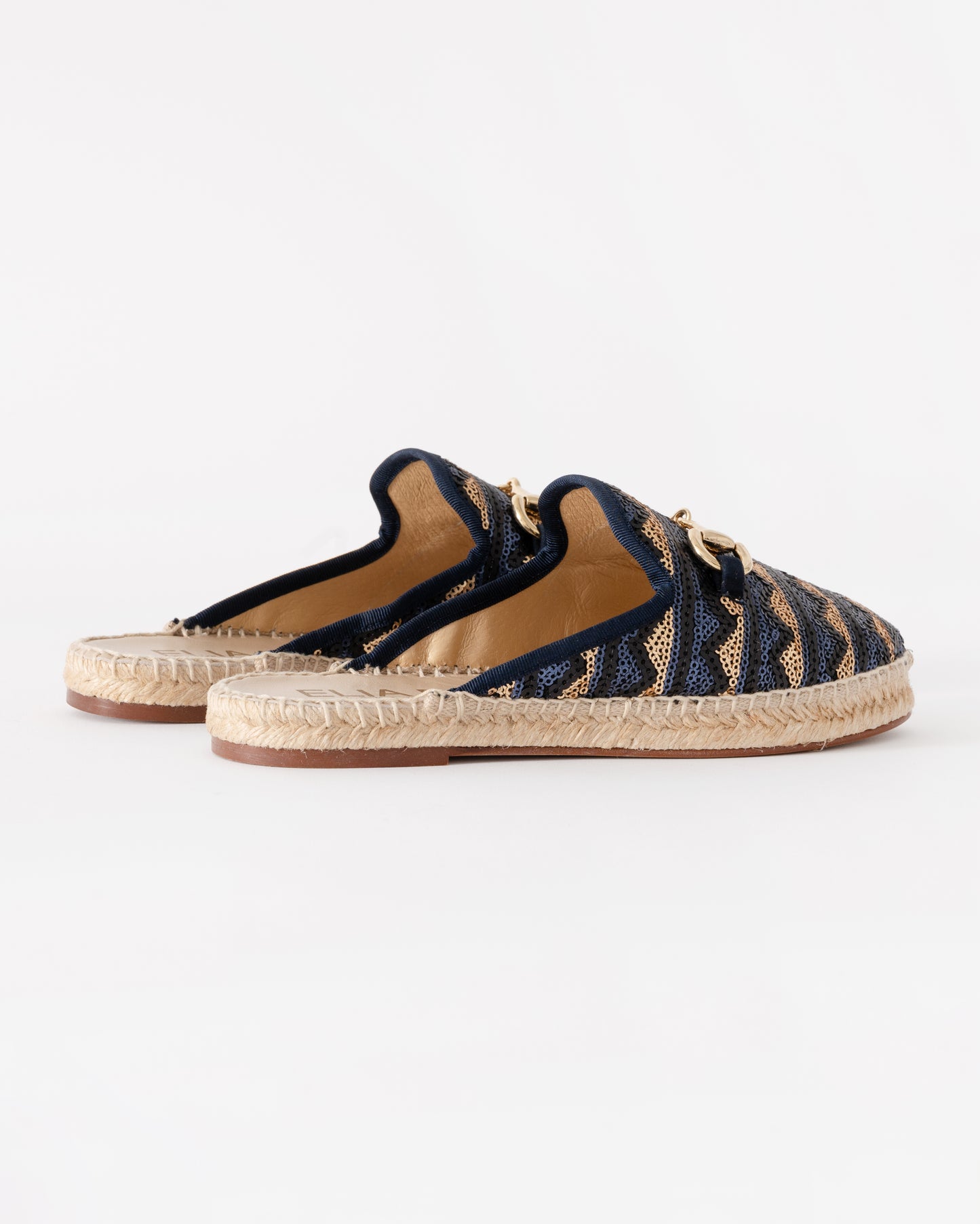 Pair of navy blue espadrilles with gold accents on a white background