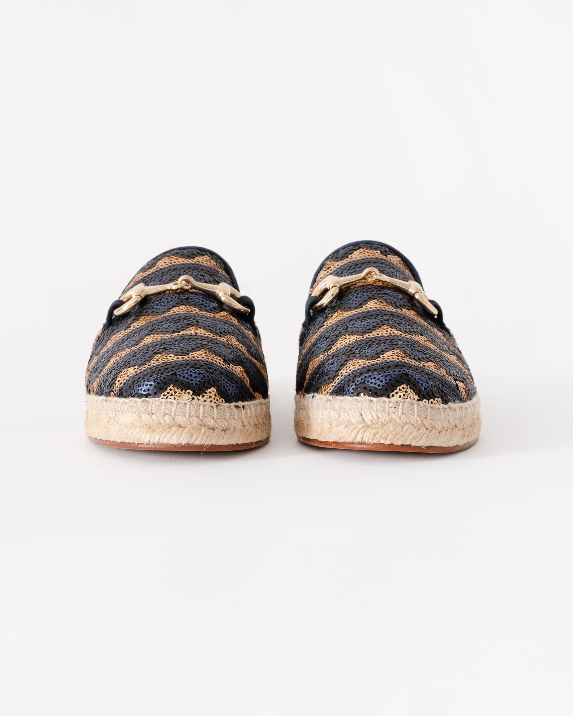 Pair of navy and gold espadrilles on a white background