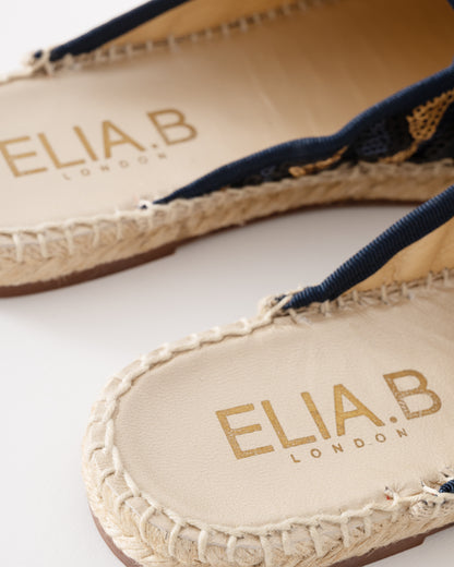 Close-up of Elia B London sandals with braided details on a white background
