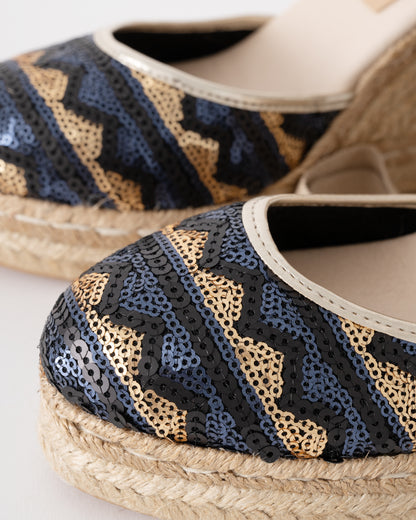 Close-up of espadrille shoes with blue and gold pattern on a white background