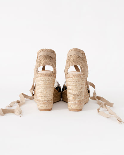 Pair of beige wedge sandals with raffia straps on a white background