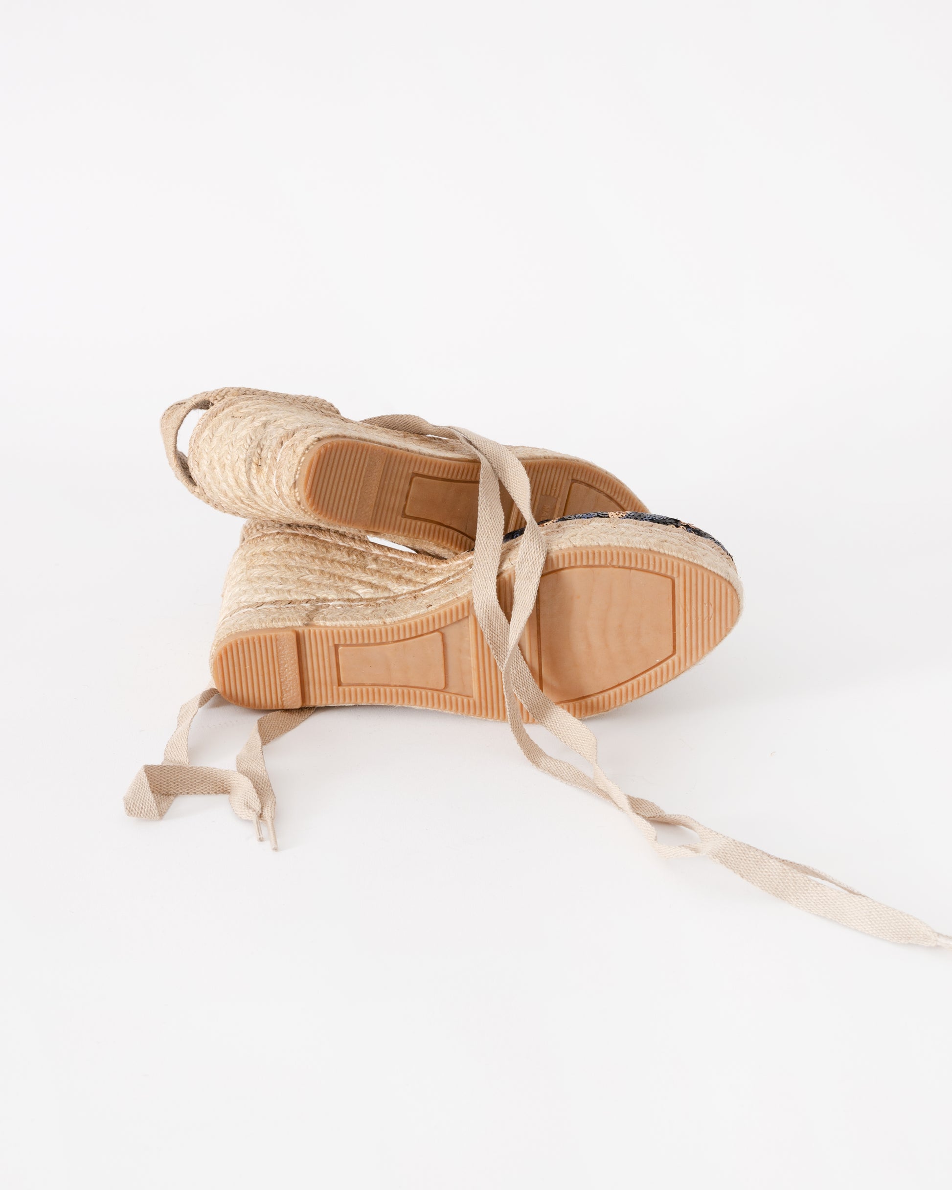 Beige espadrille shoes with woven design on a white background