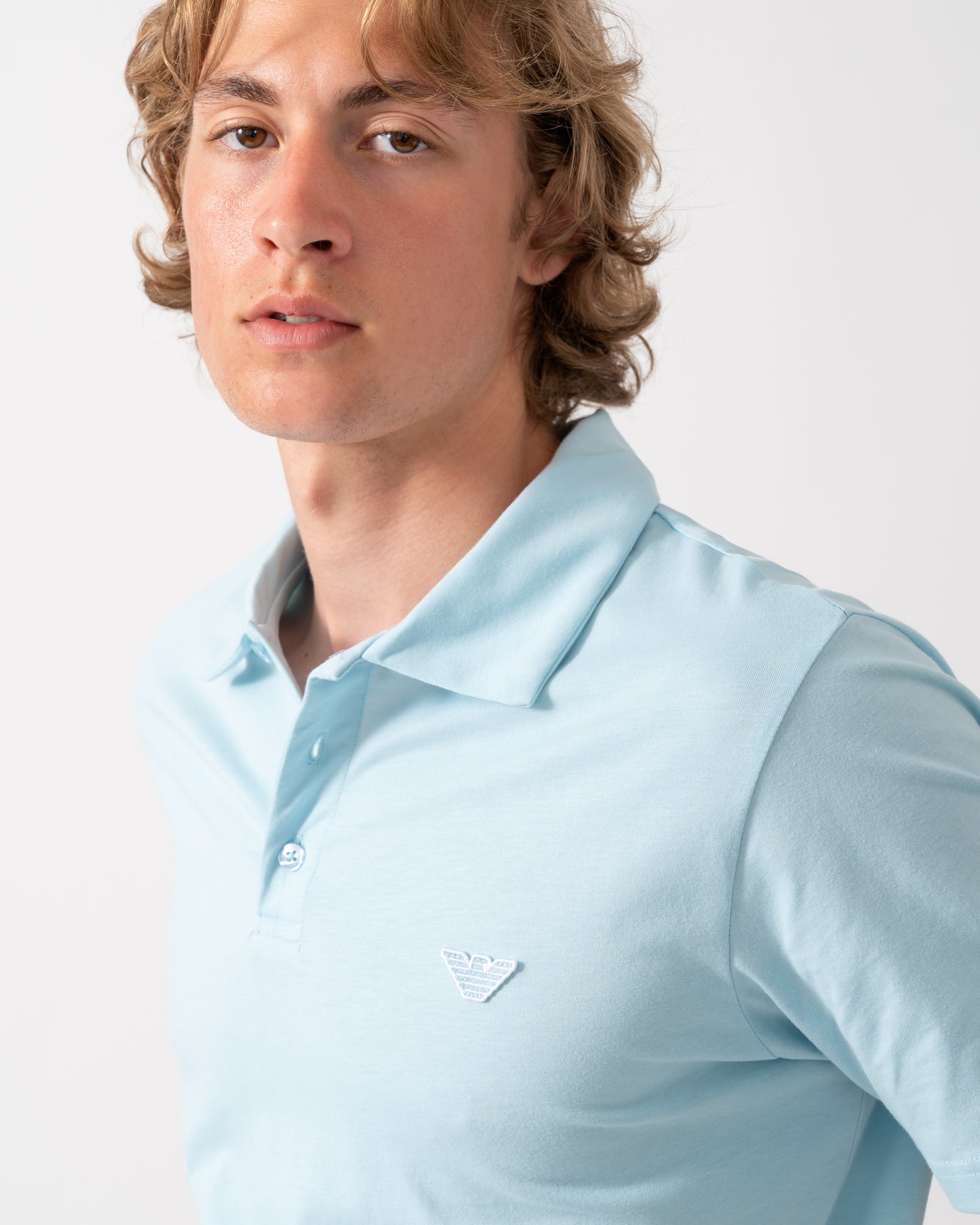 close up of a model wearing an Emporio Armani Mens Beach Polo with Eagle Logo in Sky blue