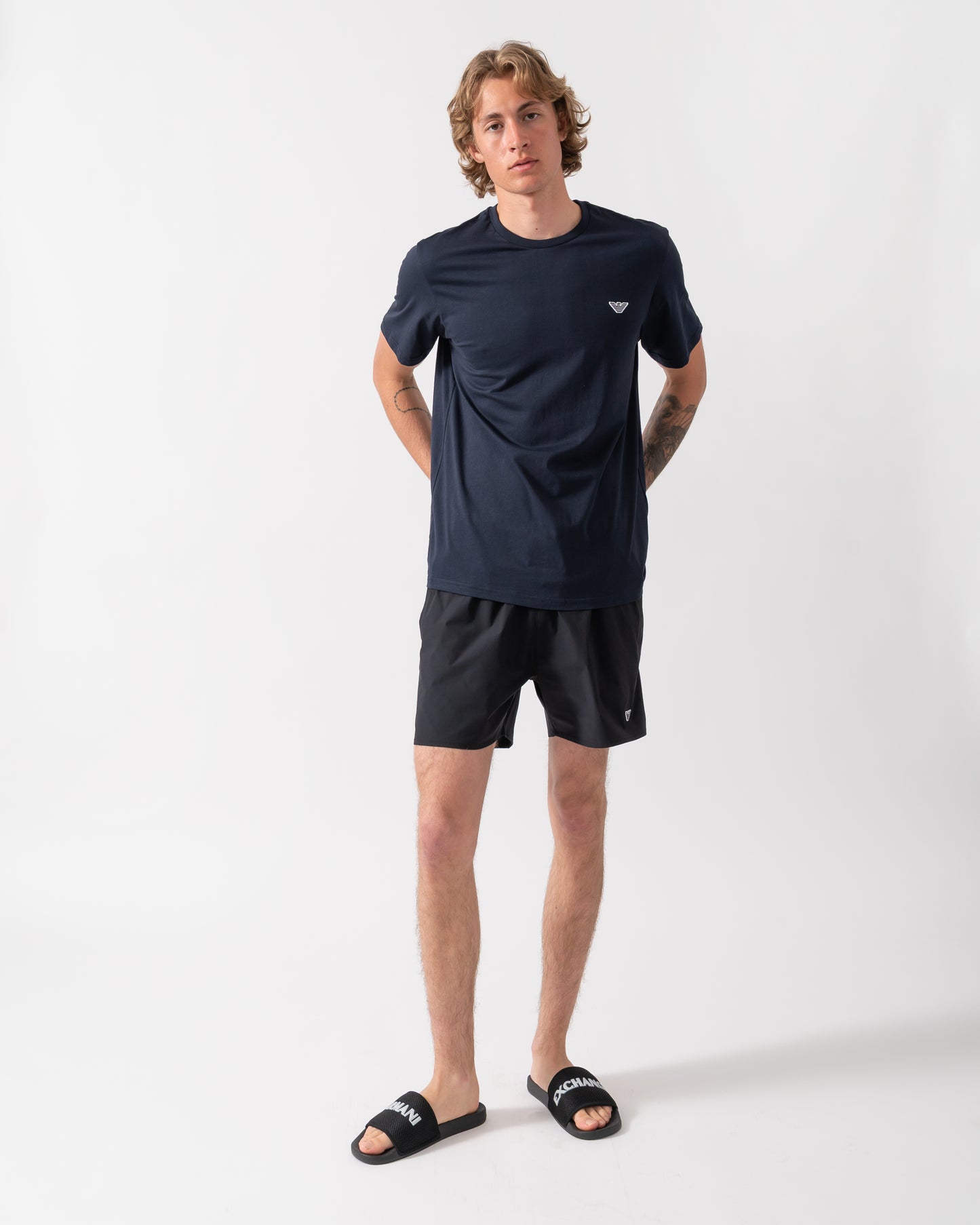 full length shot of a model wearing an Emporio Armani Mens Beach T-Shirt with Eagle Logo in Armani Blue