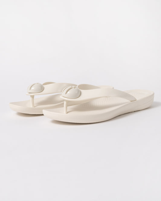a pair of FitFlop Womens IQUSHION Glossy-Button Flip-Flops in Cream 477