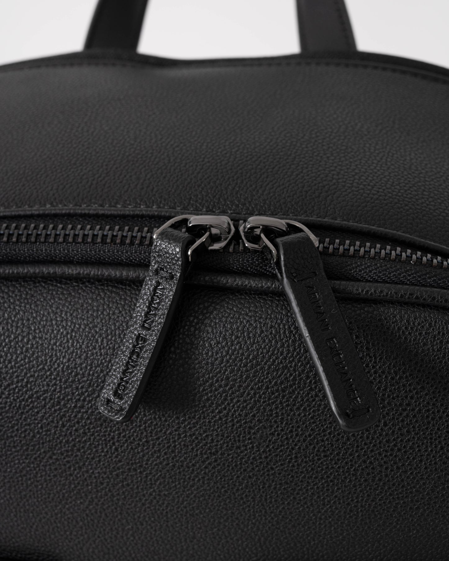 Close-up of a black backpack with zippers on a white background