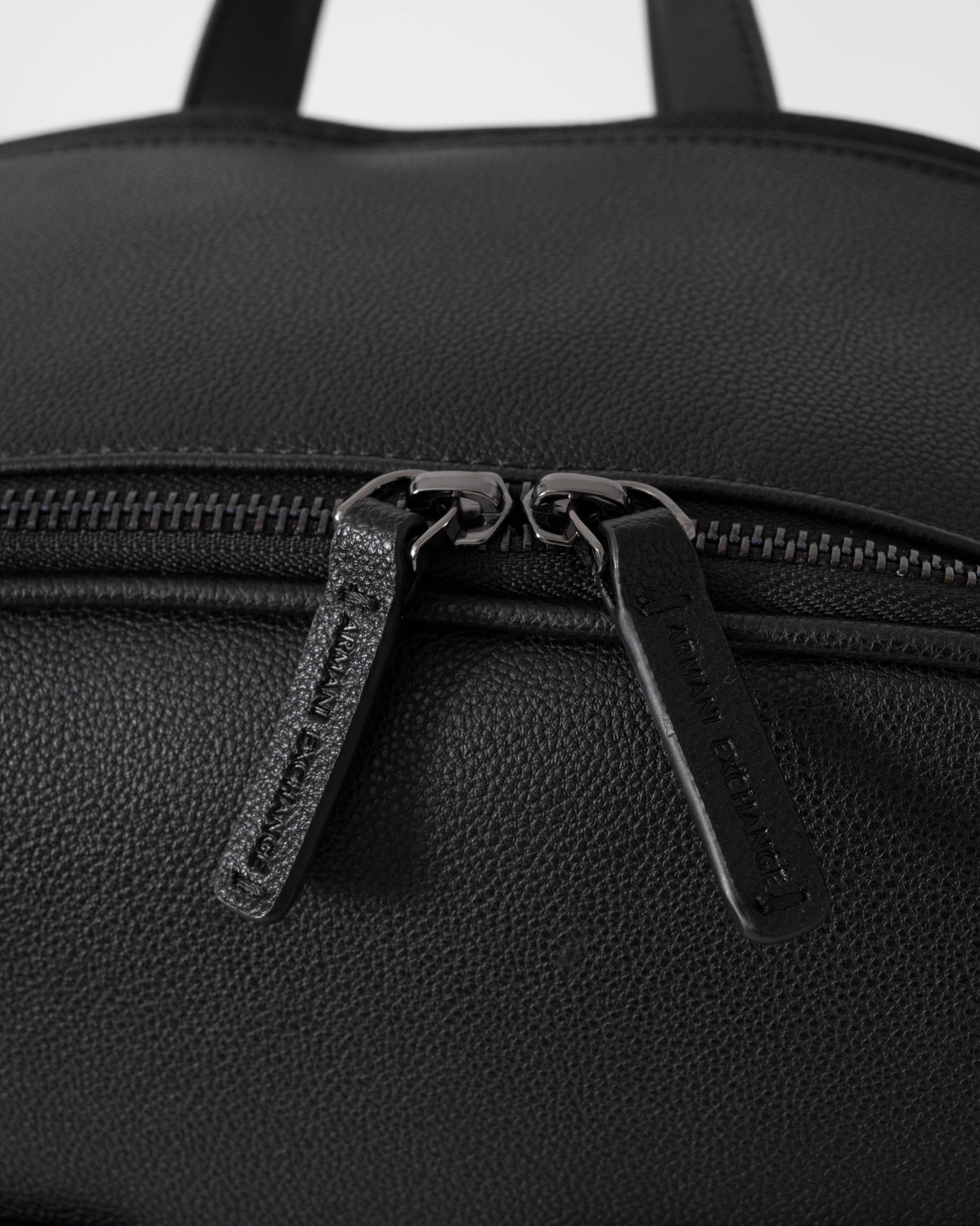 Close-up of a black backpack with zippers on a white background