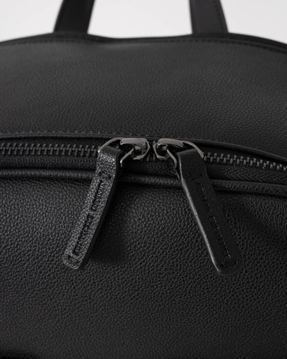 Close-up of a black backpack with zippers on a white background