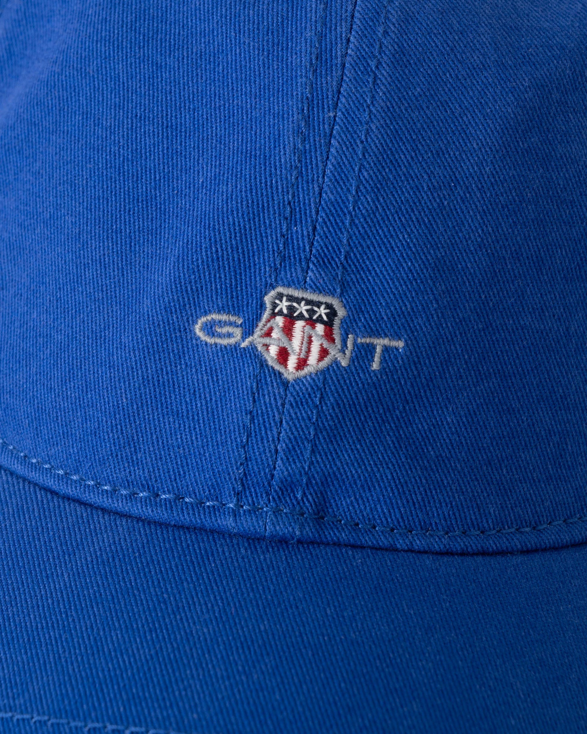 Close-up of a blue cap with GANT logo on a blue background