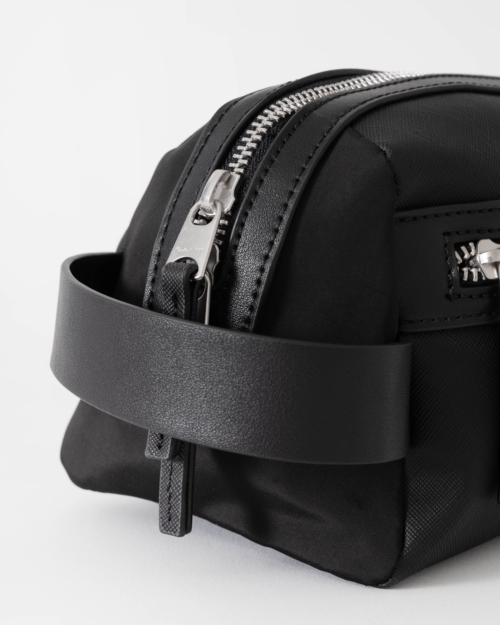 Black backpack with a zipper on a light gray background