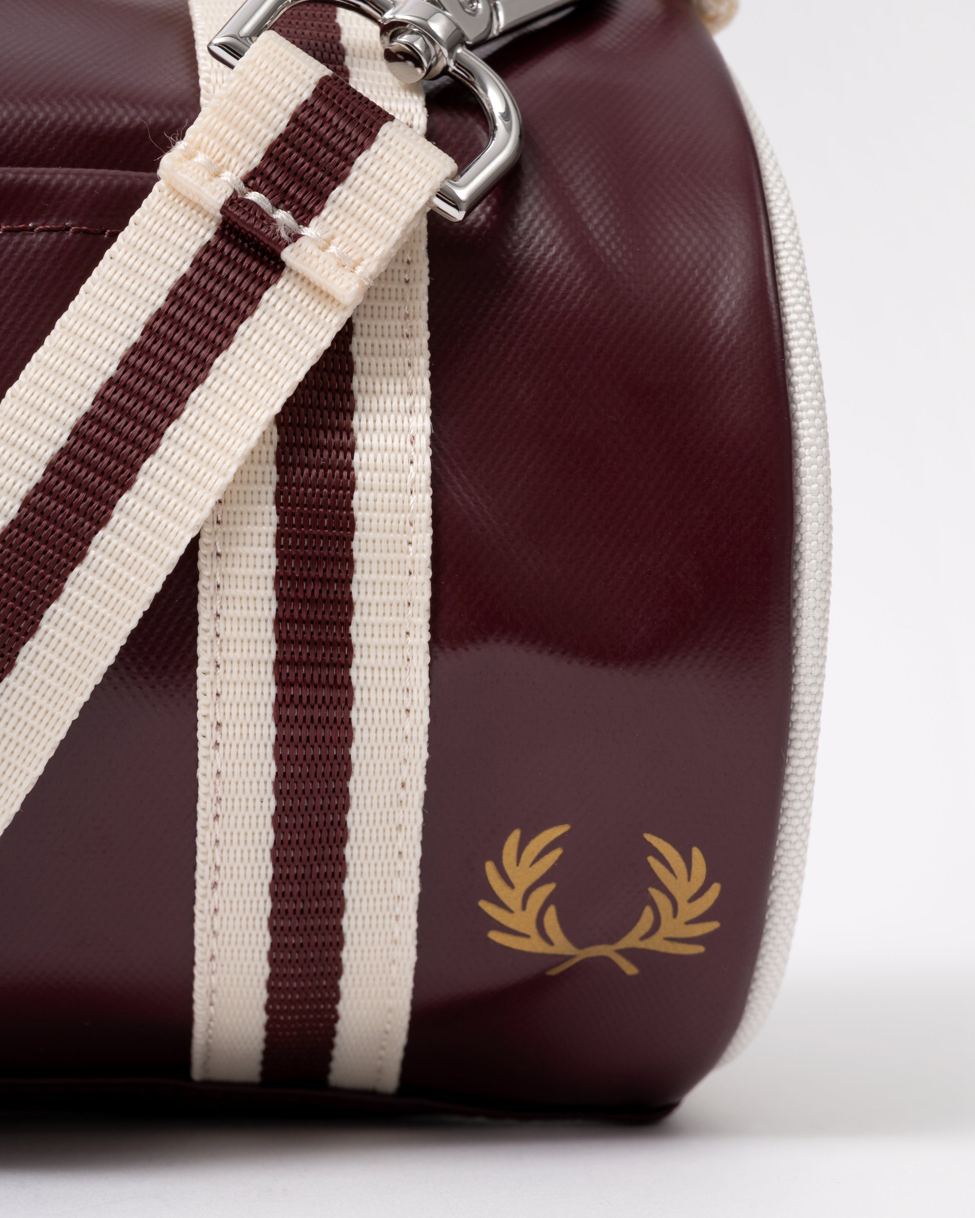 logo detail of a Fred Perry Classic Mini Barrel Bag in Oxblood and Ecru