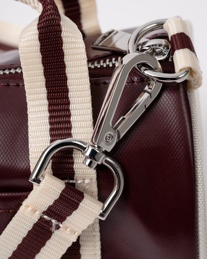 strap clip detail of a Fred Perry Classic Mini Barrel Bag in Oxblood and Ecru