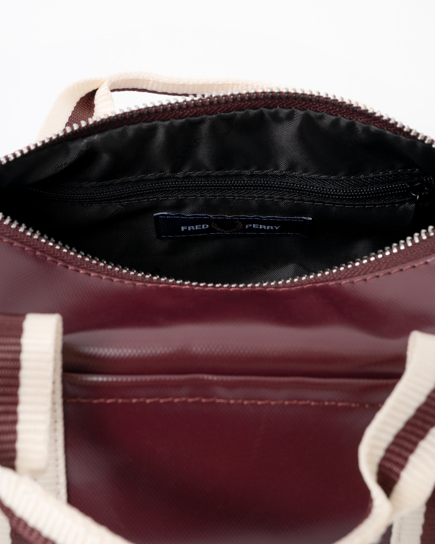 open zip of a Fred Perry Classic Mini Barrel Bag in Oxblood and Ecru