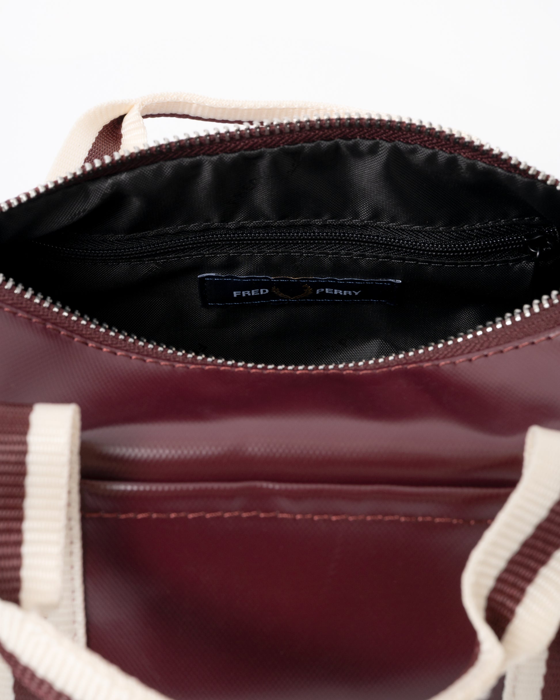 open zip of a Fred Perry Classic Mini Barrel Bag in Oxblood and Ecru