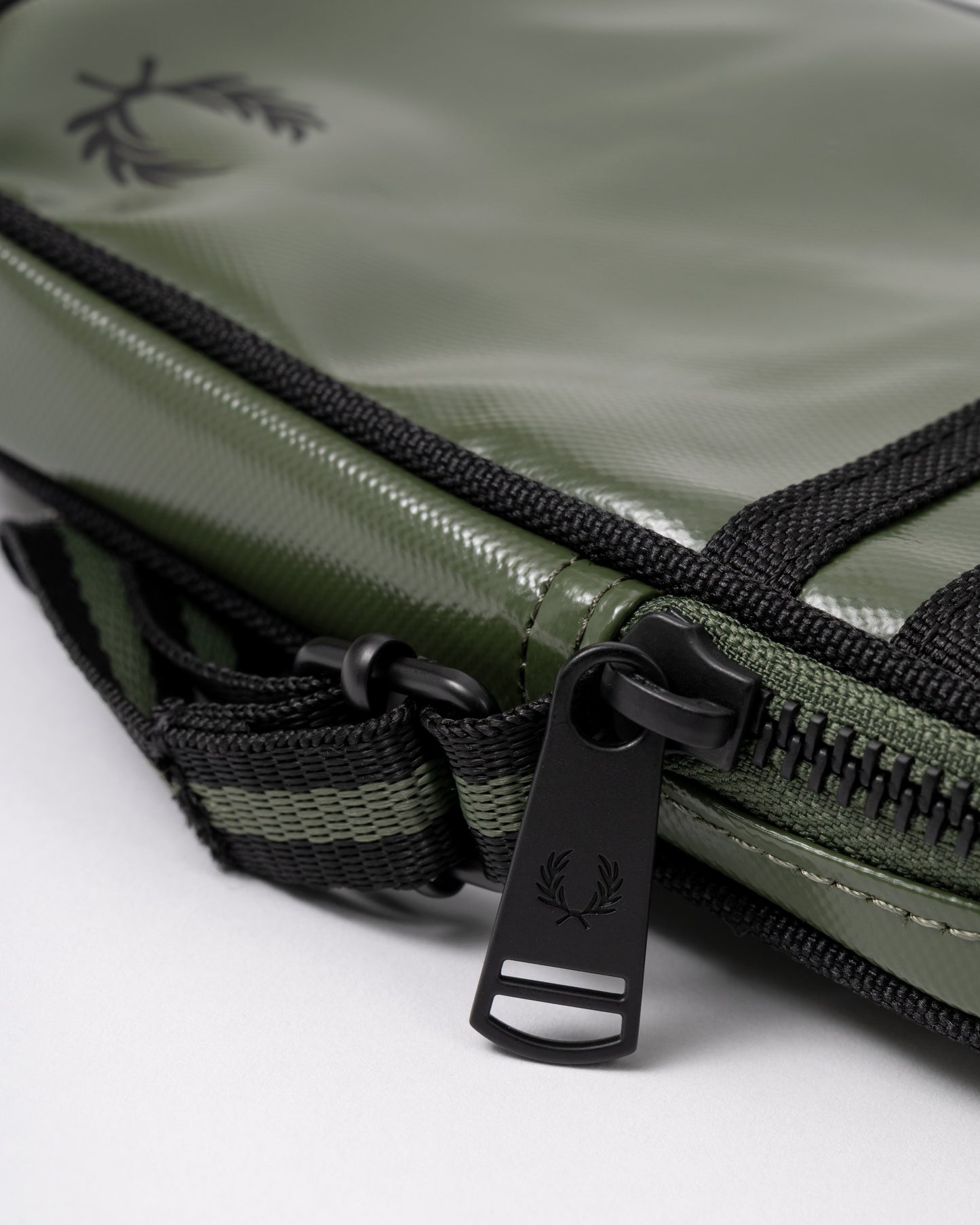 embossed zip-pull detail of a Fred Perry Classic Small Side Bag in Laurel Wreath Green and Black Z50