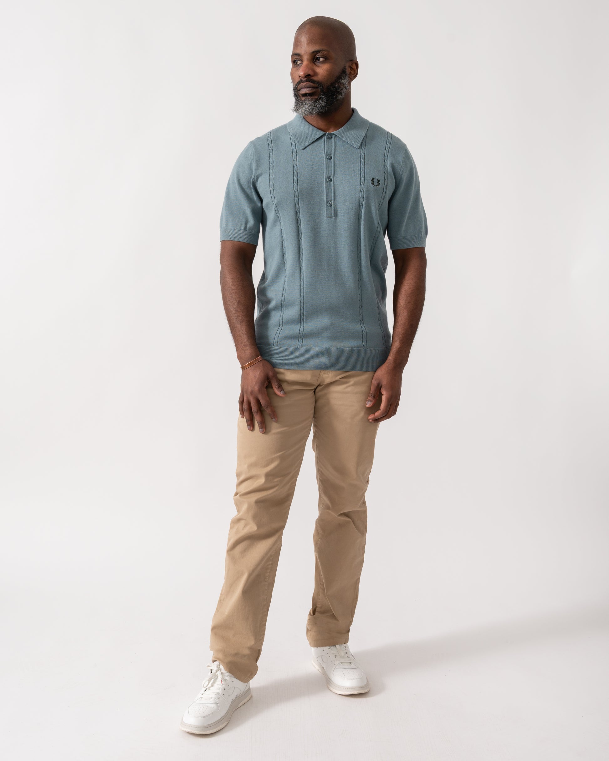 full length shot of a model wearing a Fred Perry Mens Cable Knitted Polo Shirt in Stockport Blue