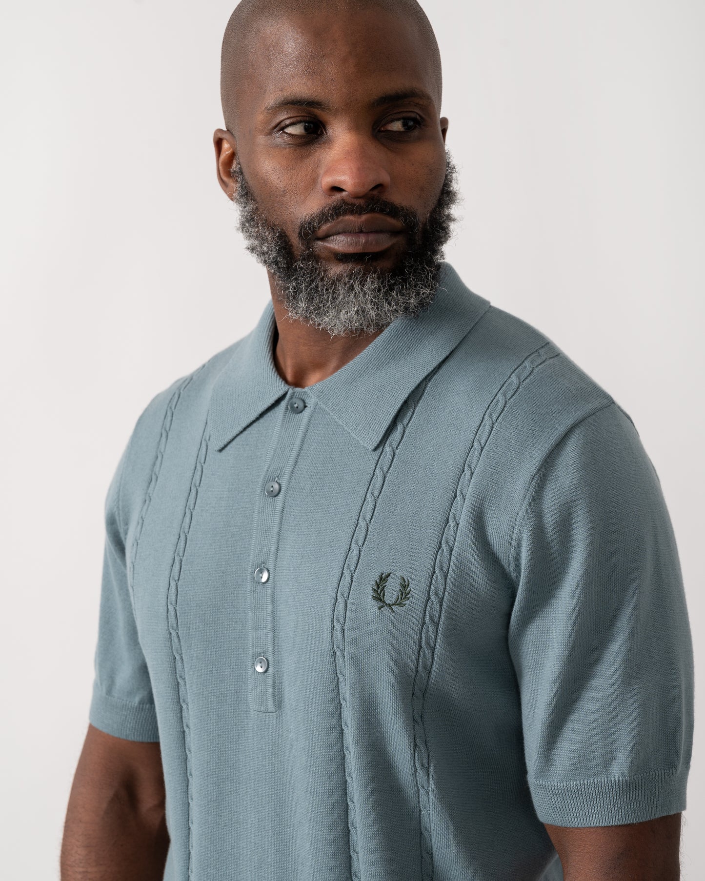 close up shot of a model wearing a Fred Perry Mens Cable Knitted Polo Shirt in Stockport Blue