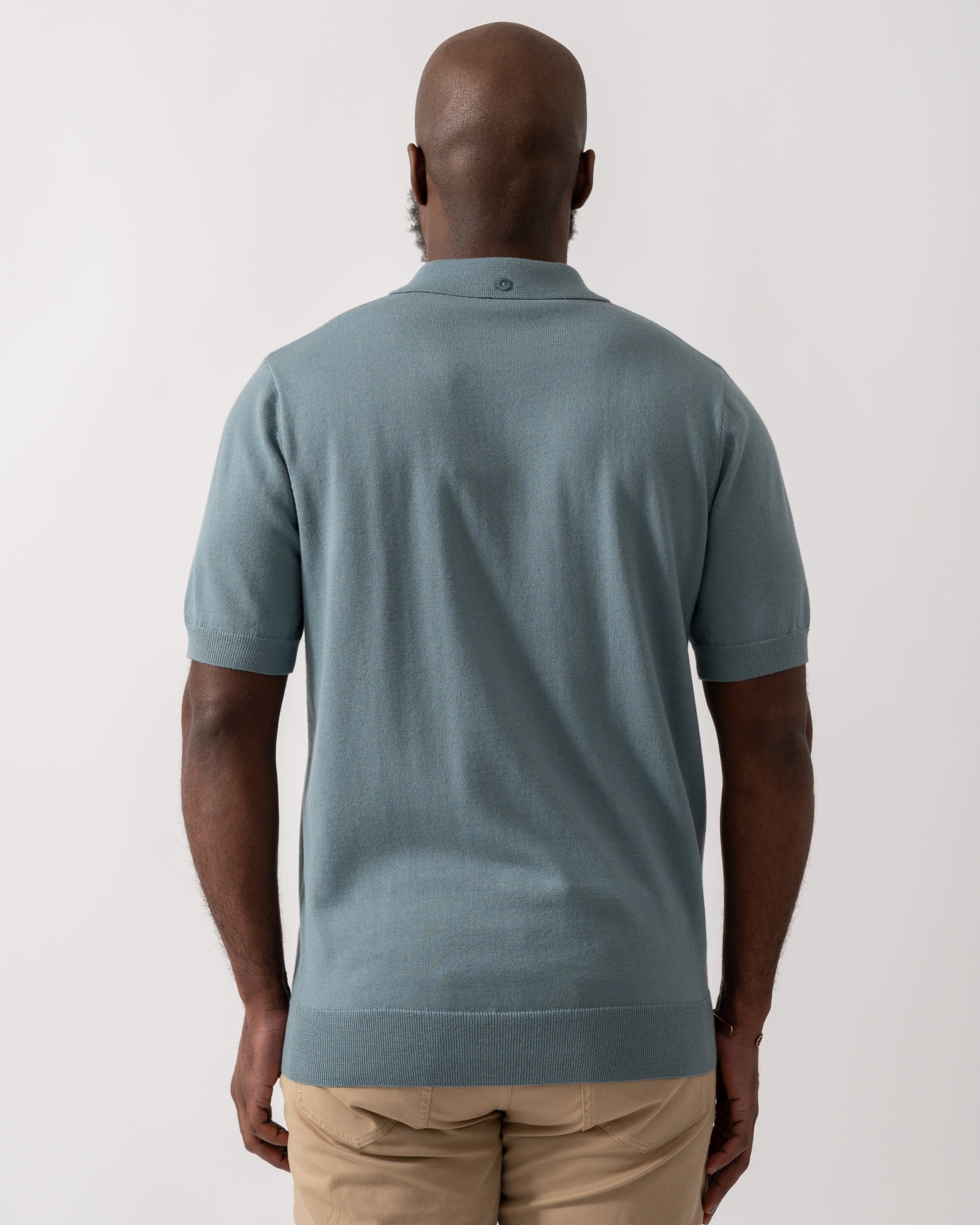 back shot of a model wearing a Fred Perry Mens Cable Knitted Polo Shirt in Stockport Blue