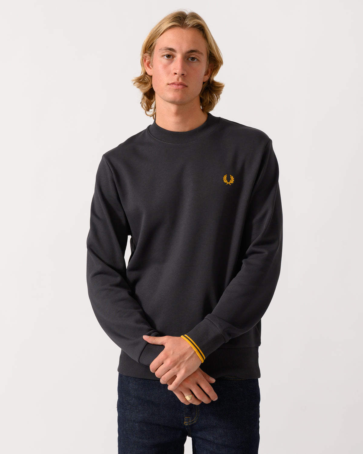 studio photograph of a model wearing a Fred Perry Mens Crew Neck Sweatshirt in Anchor Grey/Golden 85C
