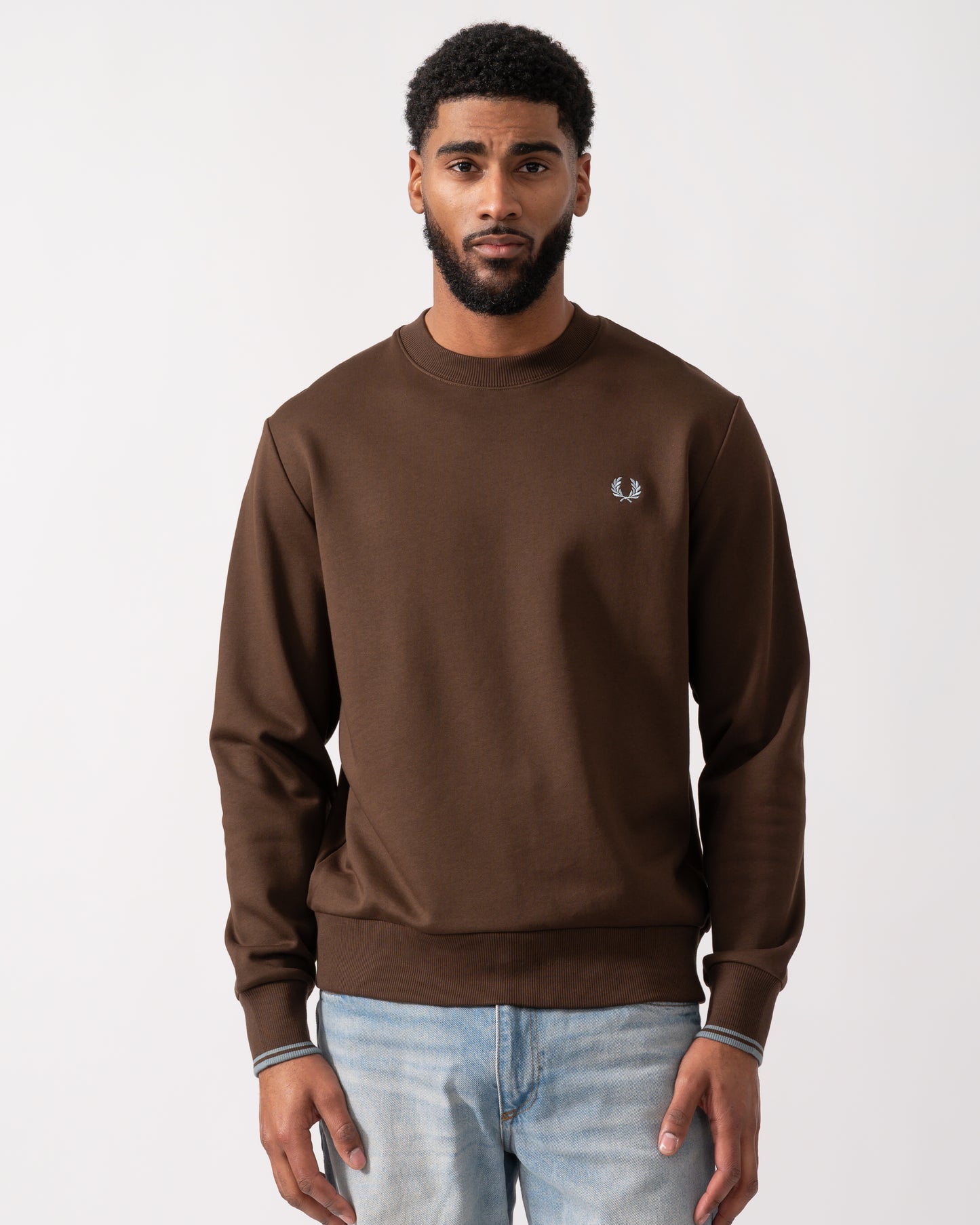 Model wearing a Fred Perry Mens Crew Neck Sweatshirt in Burnt Tobacco with Stockport Blue trim and logo