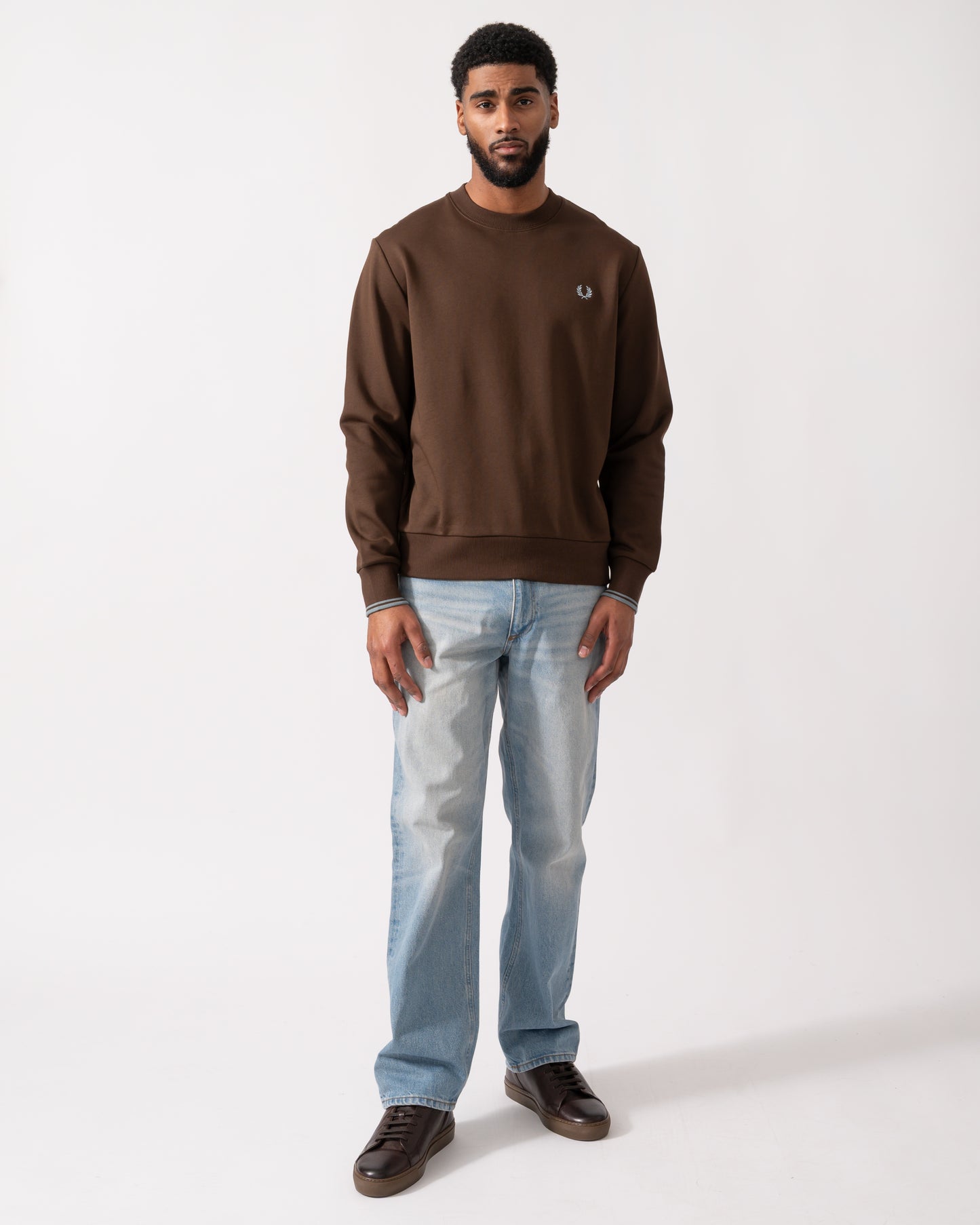 full length of a Model wearing a Fred Perry Mens Crew Neck Sweatshirt in Burnt Tobacco with Stockport Blue trim and logo