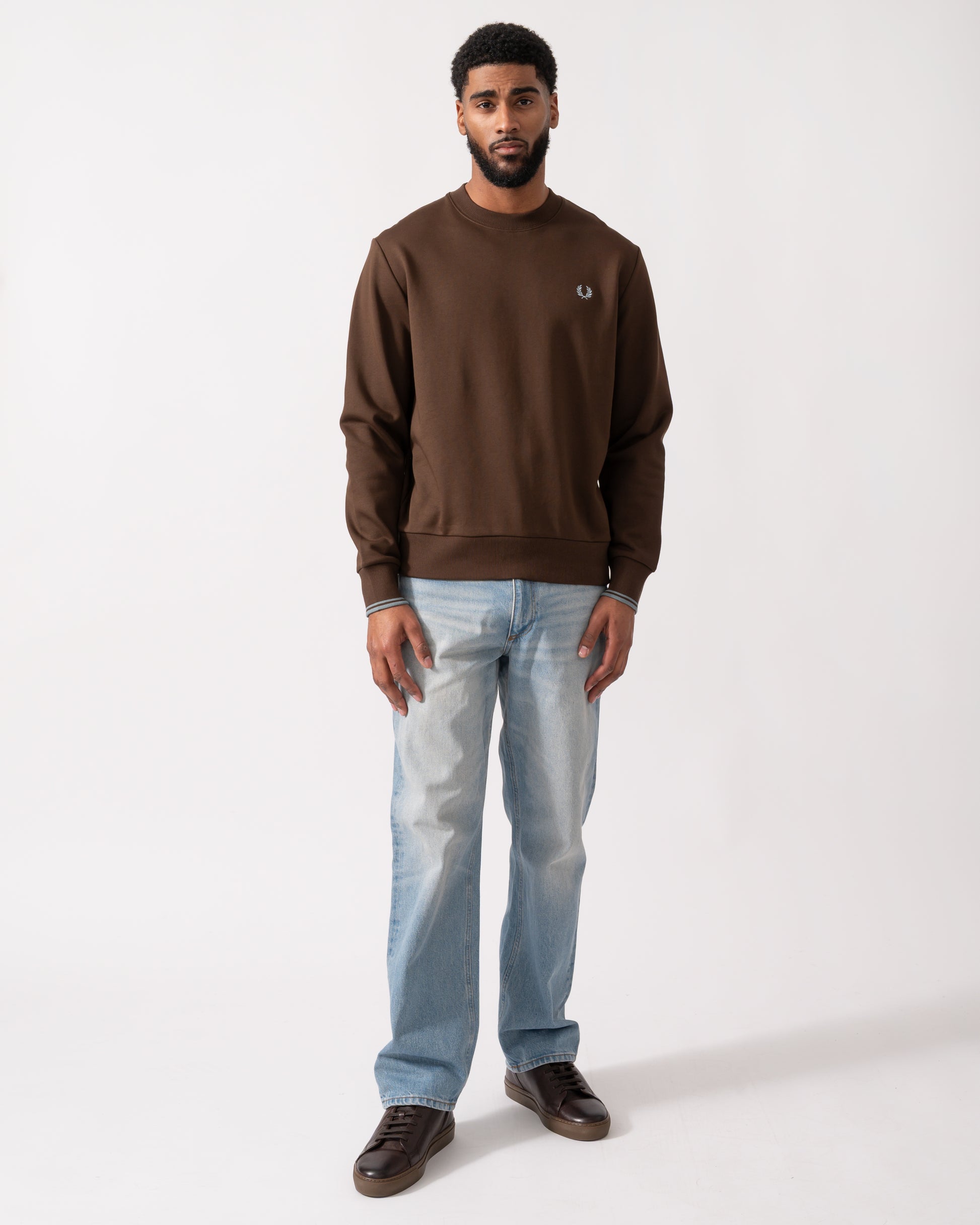 full length of a Model wearing a Fred Perry Mens Crew Neck Sweatshirt in Burnt Tobacco with Stockport Blue trim and logo