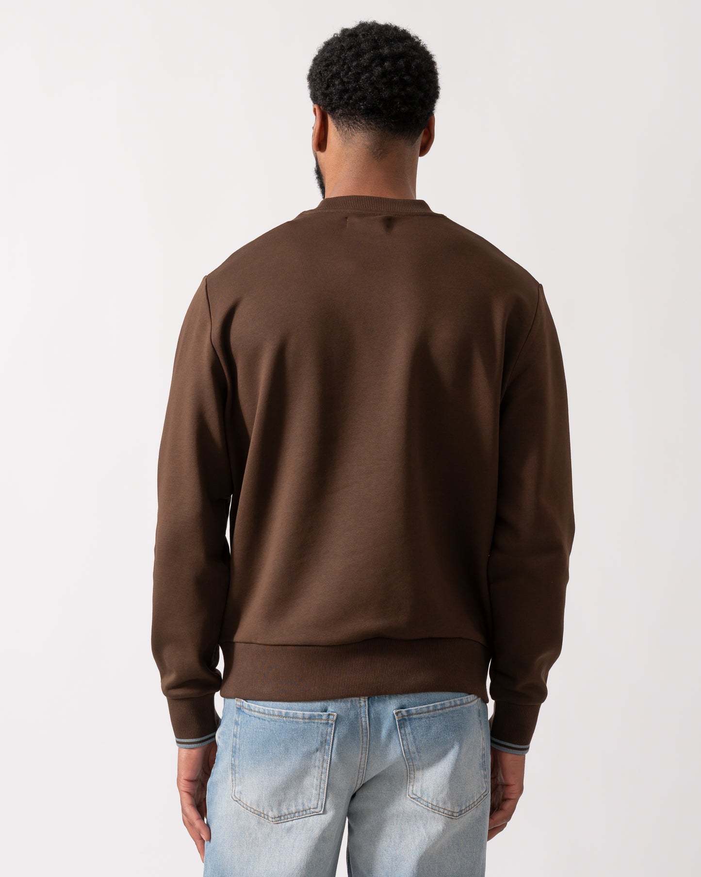 back of a Model wearing a Fred Perry Mens Crew Neck Sweatshirt in Burnt Tobacco with Stockport Blue trim and logo