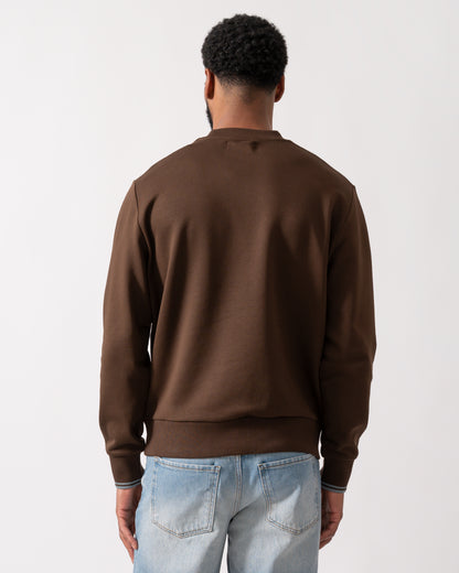 back of a Model wearing a Fred Perry Mens Crew Neck Sweatshirt in Burnt Tobacco with Stockport Blue trim and logo