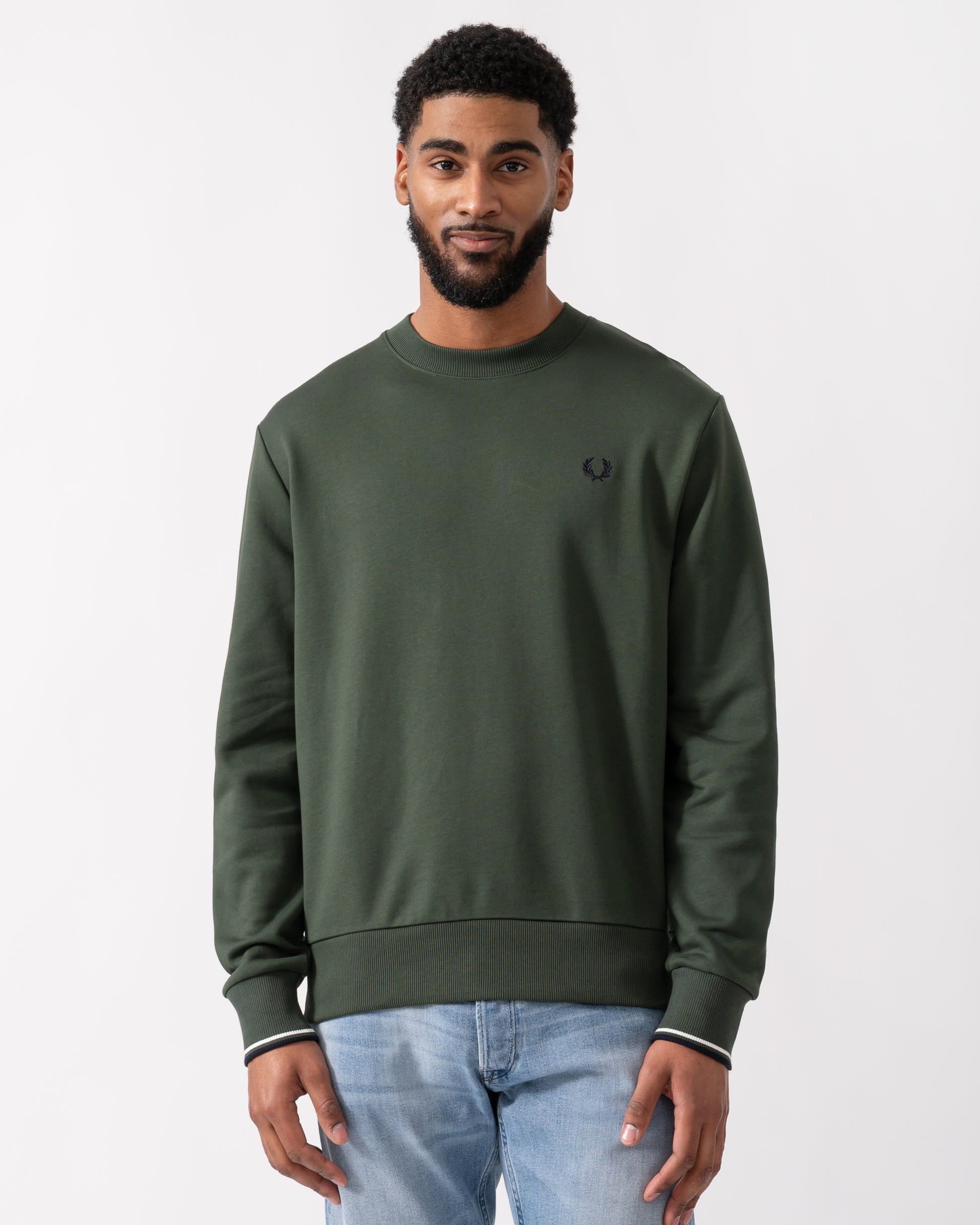 model wearing a Fred Perry Mens Crew Neck Sweatshirt in Court Green, with Snow White trim and Navy logo
