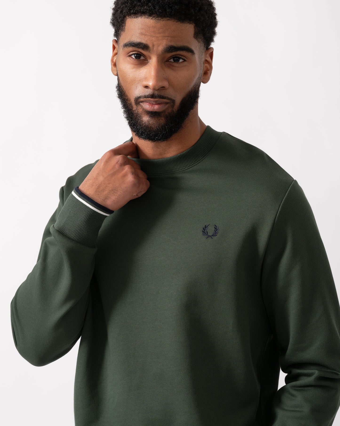 close up of a model wearing a Fred Perry Mens Crew Neck Sweatshirt in Court Green, with Snow White trim and Navy logo