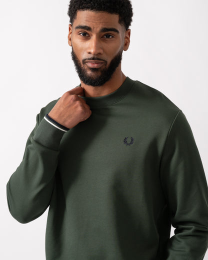 close up of a model wearing a Fred Perry Mens Crew Neck Sweatshirt in Court Green, with Snow White trim and Navy logo