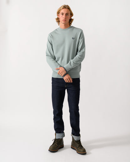 full length studio photograph of a model wearing a Fred Perry Mens Crew Neck Sweatshirt in Silver Blue/Dark Airforce 71C