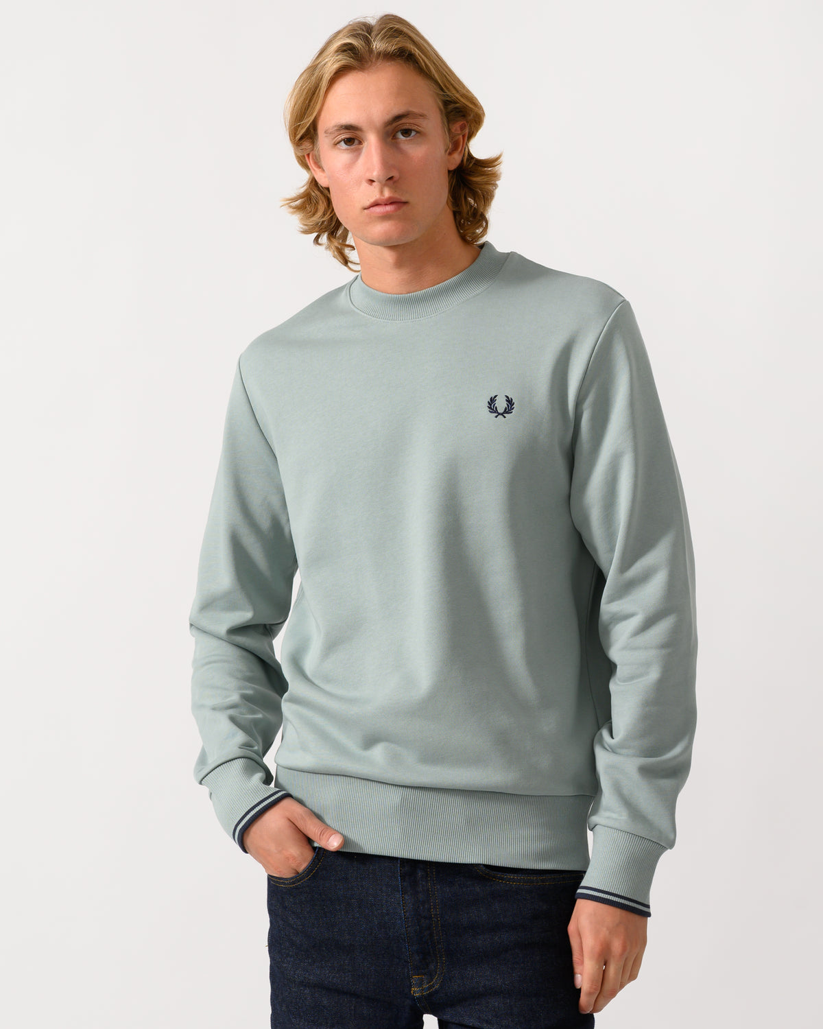 studio photograph of a model wearing a Fred Perry Mens Crew Neck Sweatshirt in Silver Blue/Dark Airforce 71C