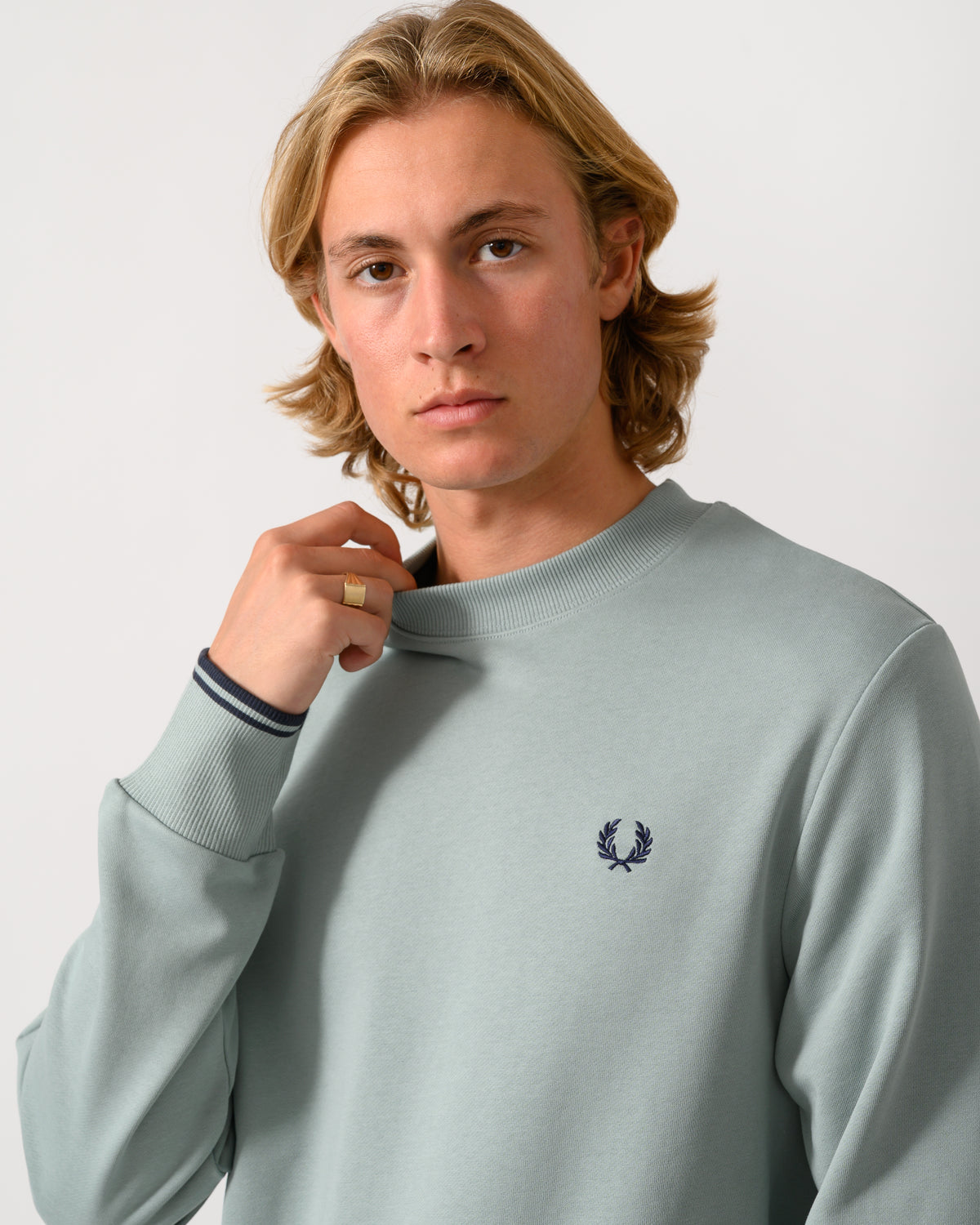 close up studio photograph of a model wearing a Fred Perry Mens Crew Neck Sweatshirt in Silver Blue/Dark Airforce 71C
