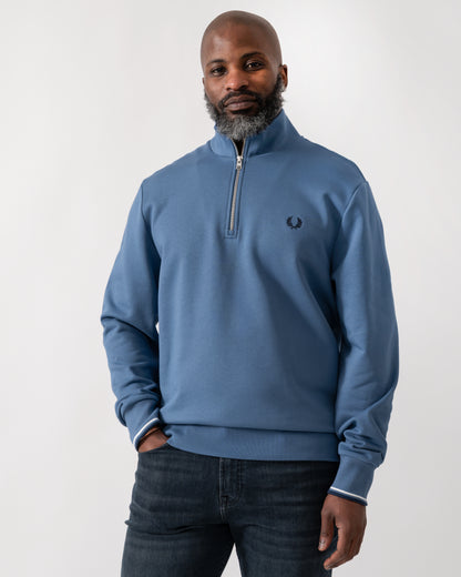 Model wearing a Fred Perry Mens Half Zip Sweatshirt in Ace Blue with Tennis Blue logo