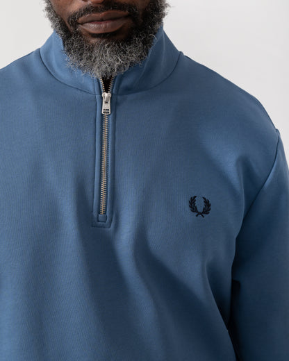 Detail shot of a Model wearing a Fred Perry Mens Half Zip Sweatshirt in Ace Blue with Tennis Blue logo
