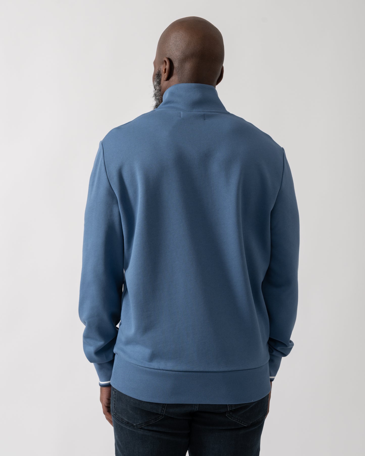 Back shot of a Model wearing a Fred Perry Mens Half Zip Sweatshirt in Ace Blue with Tennis Blue logo