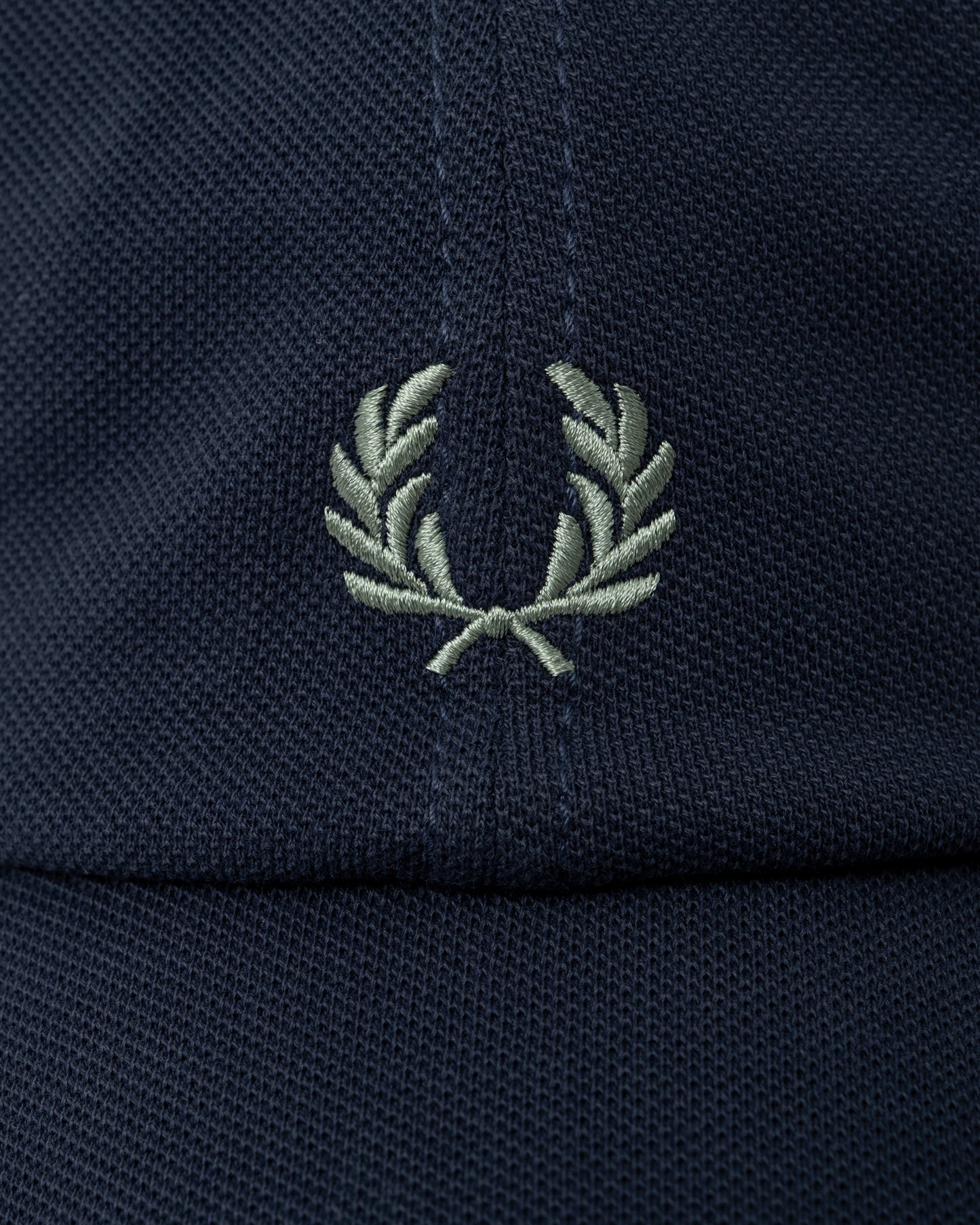 logo detail of a Fred Perry Mens Pique Classic Cap in Dark Airforce and Seagrass 90C