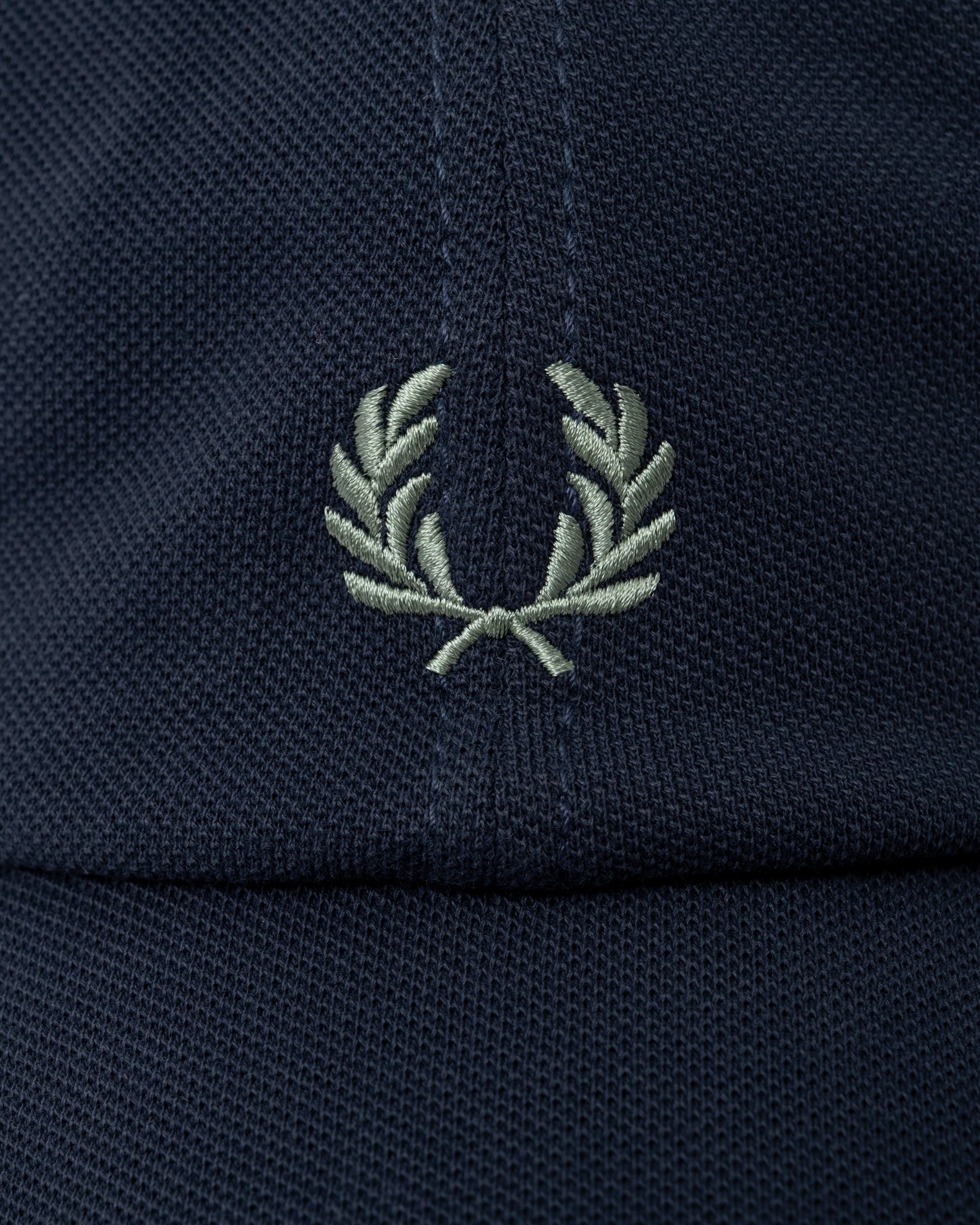 logo detail of a Fred Perry Mens Pique Classic Cap in Dark Airforce and Seagrass 90C