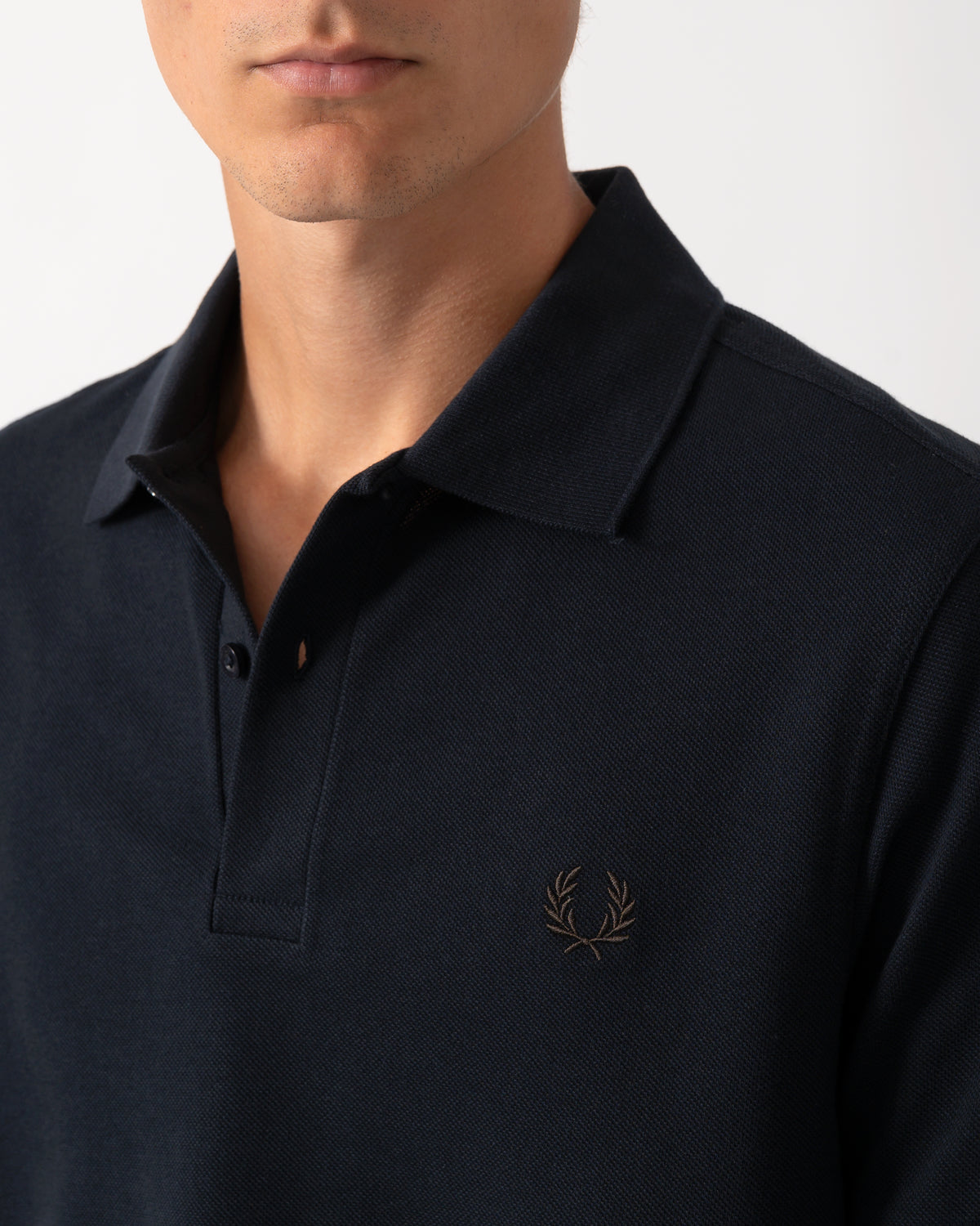 close up model wearing a Fred Perry Mens Plain Signature Polo Shirt in Navy with Rich Brown trim