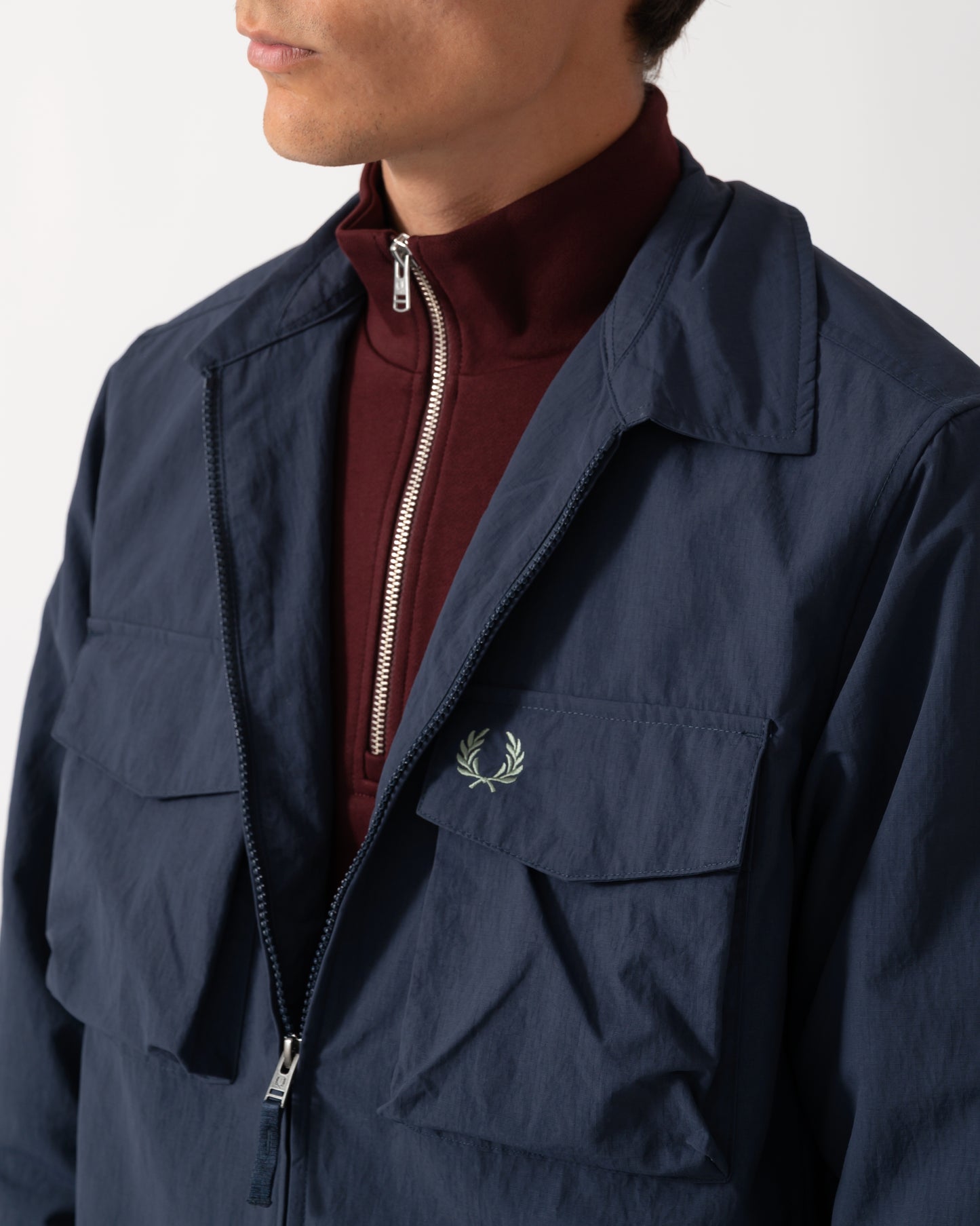 close up of a model wearing a Fred Perry Mens Ripstop Pocket Overshirt in Dark Airforce 738