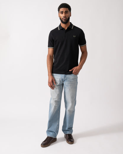 full length of a model wearing a Fred Perry Mens Twin Tipped Signature Polo Shirt in Black with Ecru and Laurel Wreath Green trim