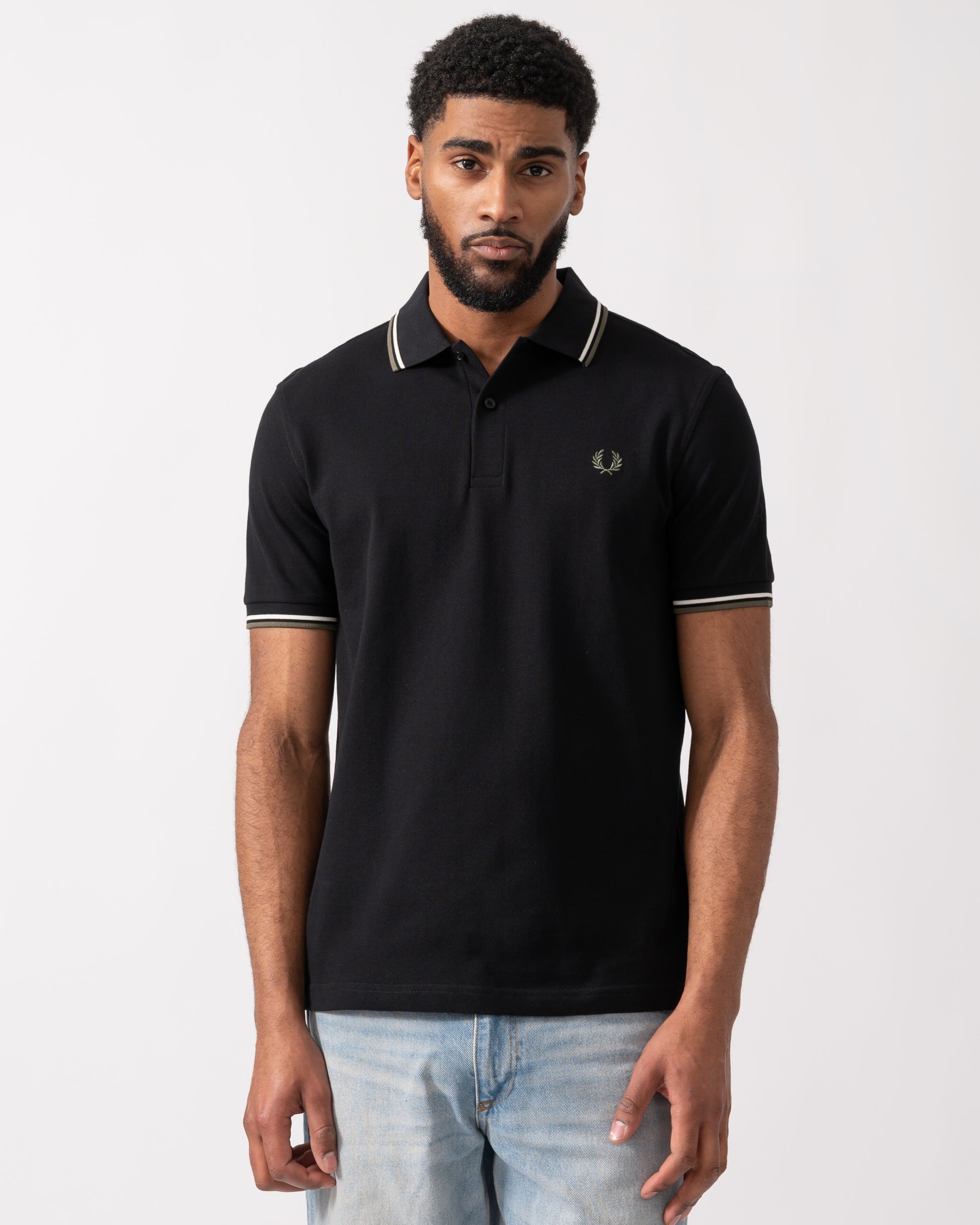 model wearing a Fred Perry Mens Twin Tipped Signature Polo Shirt in Black with Ecru and Laurel Wreath Green trim