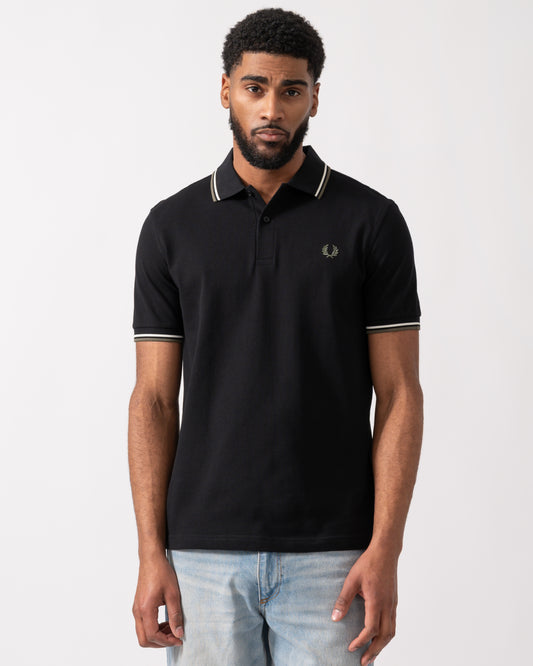 model wearing a Fred Perry Mens Twin Tipped Signature Polo Shirt in Black with Ecru and Laurel Wreath Green trim