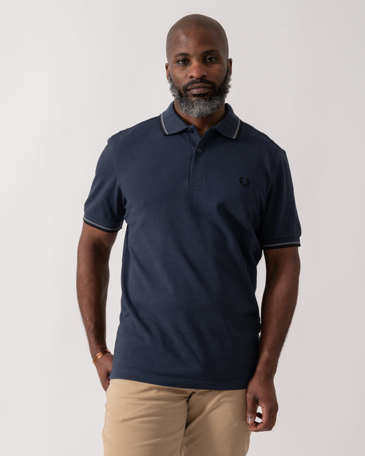 model wearing a Fred Perry Mens Twin Tipped Signature Polo Shirt in Dark Airforce with Stockport Blue and Black trim