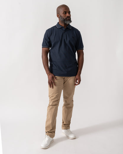 full length shot of a model wearing a Fred Perry Mens Twin Tipped Signature Polo Shirt in Dark Airforce with Stockport Blue and Black trim