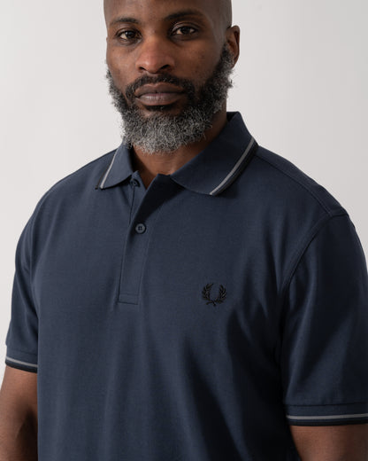 detail shot of a model wearing a Fred Perry Mens Twin Tipped Signature Polo Shirt in Dark Airforce with Stockport Blue and Black trim